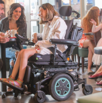 A woman using a TDX SP2 power chair laughs in a cafe with her friends thumbnail